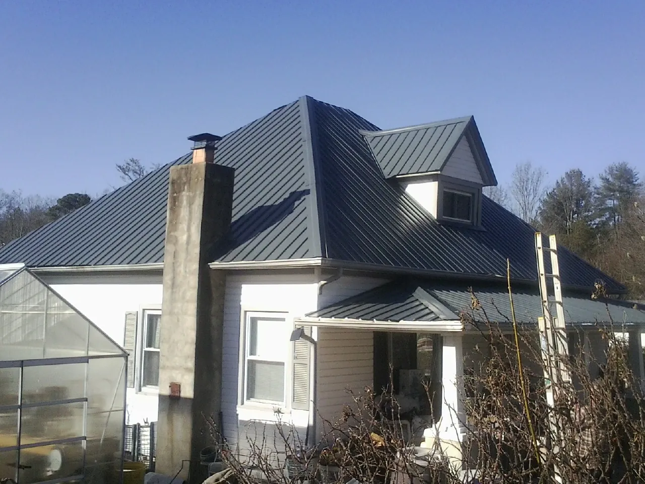 Dark blue standing seam metal roof on a white farmhouse with dormer — Slate & Tile Roof Repair by Roofing Brothers in Waukegan