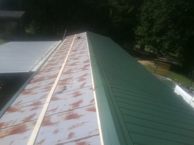 Old rusted panels beside newly installed green metal roofing — Wind Damage Roof Repair by Roofing Brothers in Waukegan