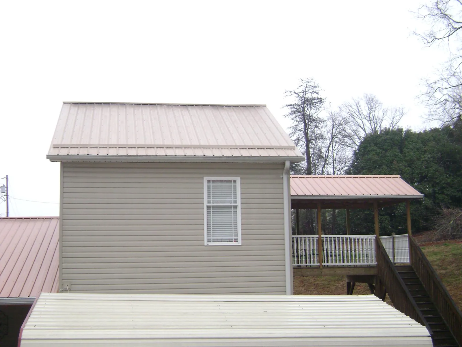 Tan metal roofs on a two story addition and attached porch, from a Roof Replacement job in Waukegan