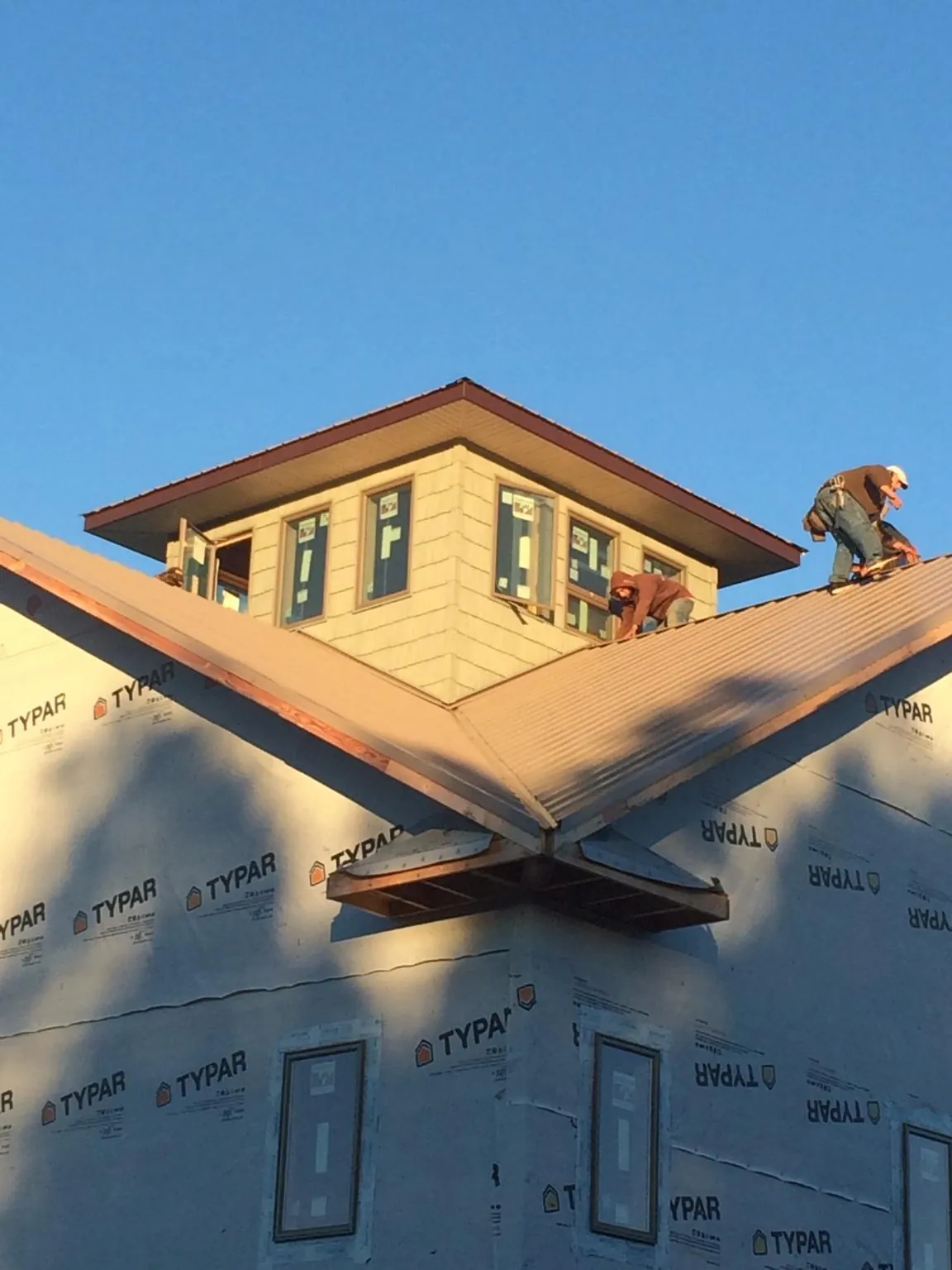 Roofers working around a rooftop cupola on a new metal roof at sunset — Roof Waterproofing in Waukegan by Roofing Brothers